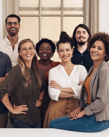 Diverse team of four smiling professionals standing together in a bright office hallway