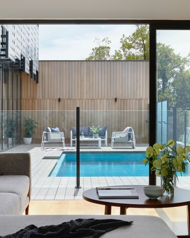Spacious shared living room with blue sofas, tile floors, and large windows letting in natural light